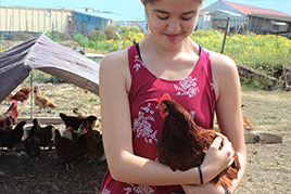 young girl holding a brown hen