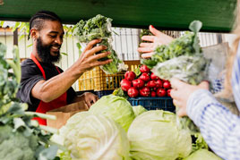 a grocer helps a customer with vegetables